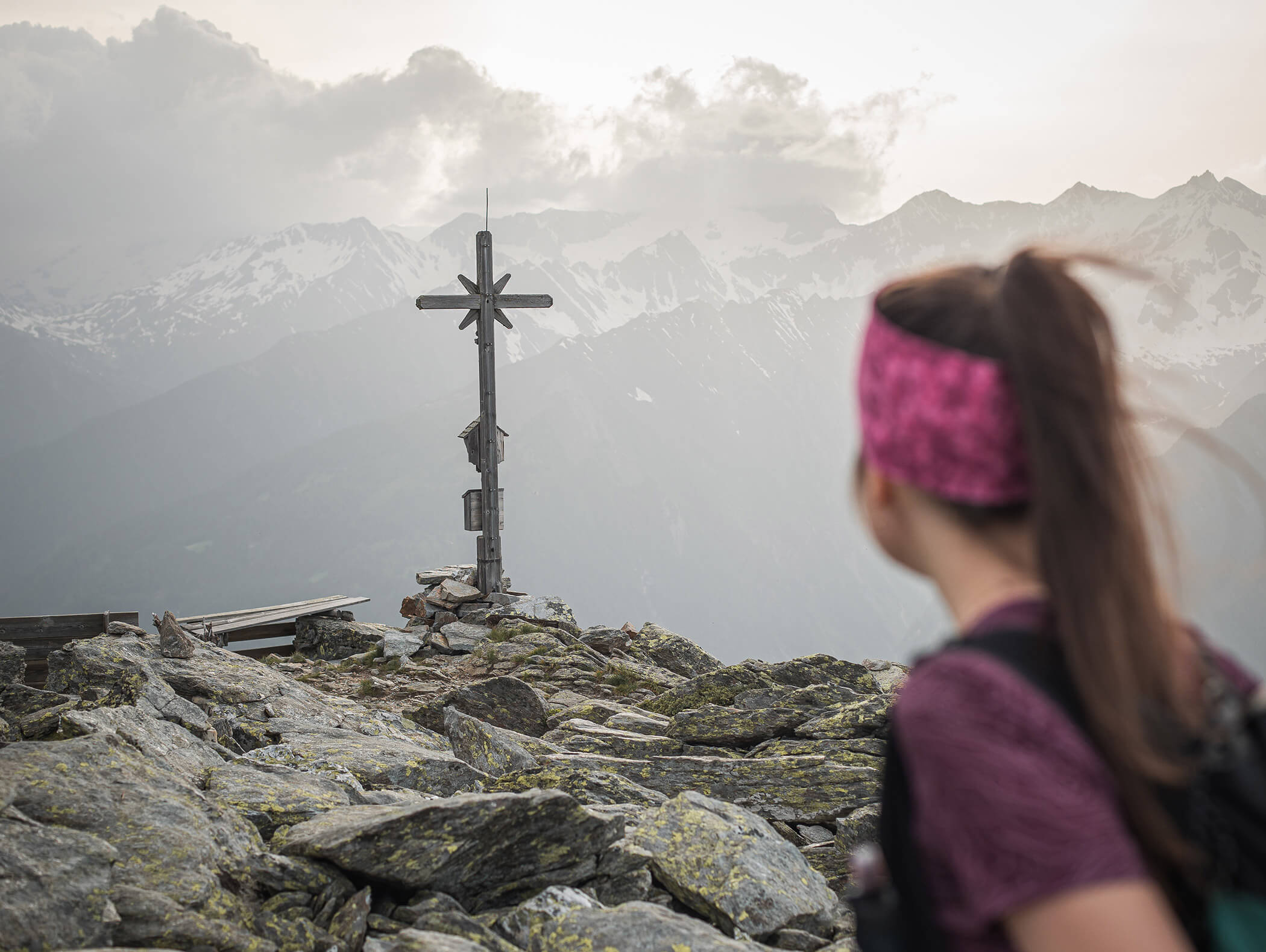 Donna guarda la croce di vetta e la fantastica vista sulle montagne innevate - Pensione Oberwirt