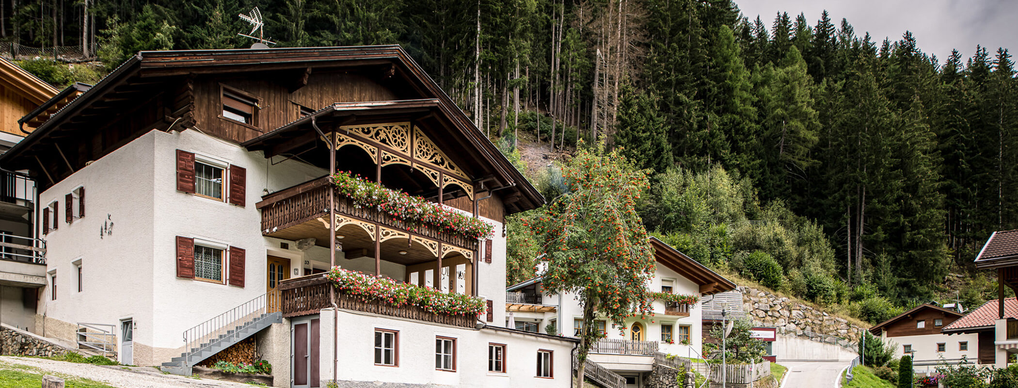The Pension Oberwirt from the outside with balcony flowers and an apple tree next to it