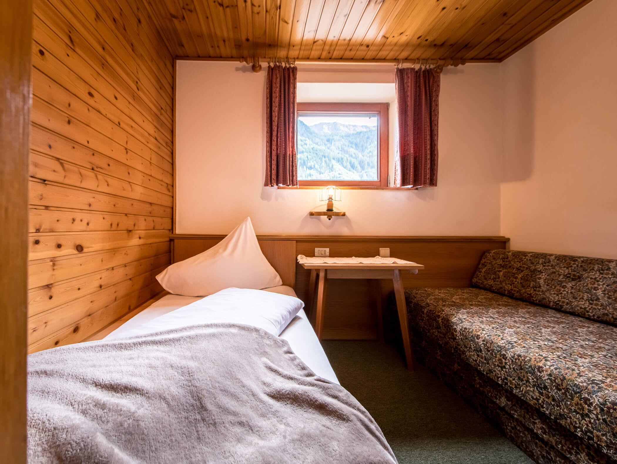 Camera singola con coperta, tavolo e divano - Pensione Oberwirt