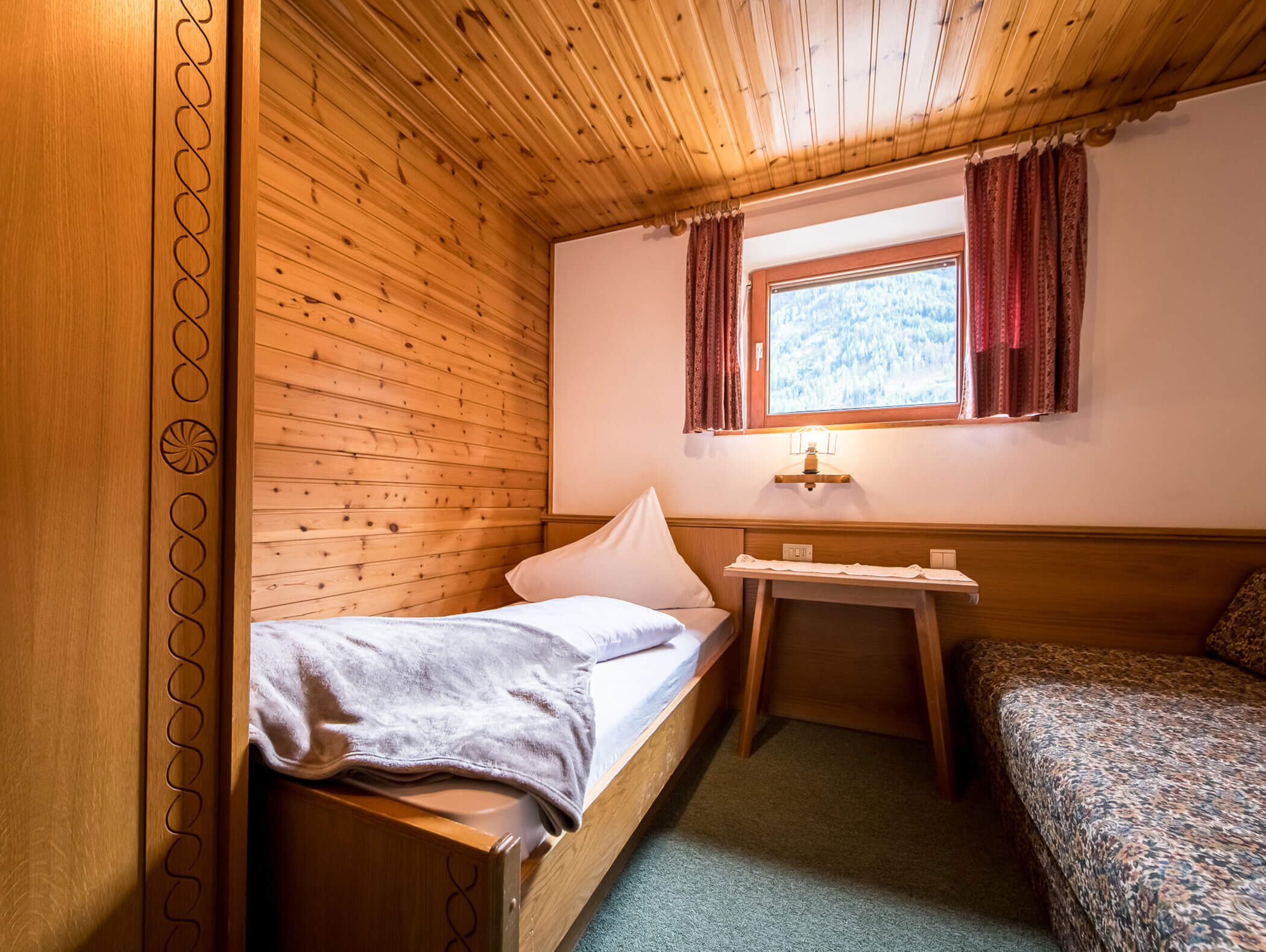 Camera singola con coperta accogliente, tavolo e divano - Pensione Oberwirt